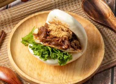 Kaplan gümüş domuz sandviçini ısırdı. Tahta tabakta servis edildi. Tayvan yemeği masasının kenarından izole edildi.