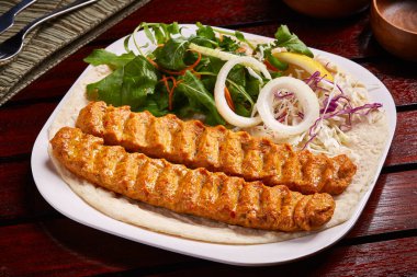 Baharatlı bbq kuzu kebabı, salata, limon ve ekmek ile servis edilir.