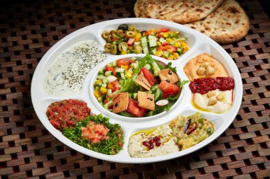 Marmaris Cold Mezza 'nın Orta Doğu yemekleri masasının yanında servis edilen ekmek ve salatayla servis edilmiş hali.