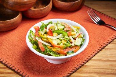 Marmaris Karışık Salata ve Salatalık. Tabakta servis edilen mısır, domates ve yeşil yapraklar, orta doğu yemekleri masasının yan tarafında.