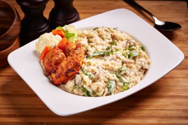 Risotto mantarı ve tavuk kübü, orta doğu yemekleri masasının yanında izole bir şekilde servis edilir.