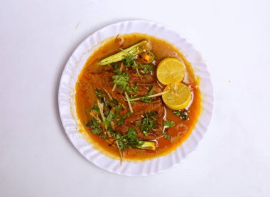 Nihari tavuğu, servis edilen limon dilimli gri arka planda servis edilen Pakistan yemekleri.
