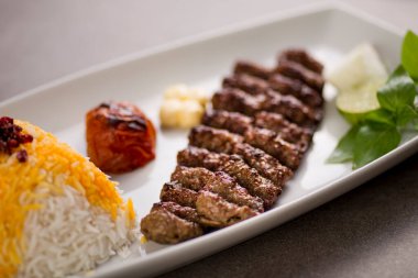 Biryani pilavlı chelo kebabı ve gri arka plandaki Arap yemeklerinin üst görüntüsünde servis edilen salata.