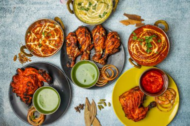 Tavuk Tikka Butter Masala, Reshmi masala, Ginger Chicken, Tangri Kebap, Lal Badsha, tandoori, Peri peri, biber soslu, gri arka planda bangladeş yemeklerinin üst manzarasında izole edilmiş bir tabakta servis ediliyor.