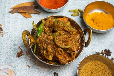 Baharatlı Karahi tavuğu ve masala tozu gri arka planda izole edilmiş bir tabakta servis ediliyor. Bangladeş yemeklerinin üst manzarası.