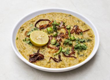 Tabakta kızarmış soğan ve limon ile servis edilen tavuk haleem Hint ve Pakistan baharatlı yemeklerinin üst tarafında izole edilmiş.