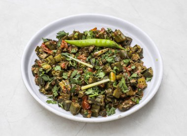 Hindistan ve Pakistan baharatlı yemeklerinin üst katında servis edilen tabakta soğanlı, zencefilli, domatesli ve yeşil biberli kızarmış bhindi veya kadın parmağı.