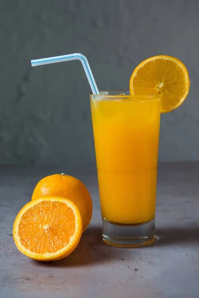 ヘルシーな新鮮な絞りオレンジのスライスと灰色の背景のわら側のビューでガラスで提供される新鮮なジュース — ストック写真