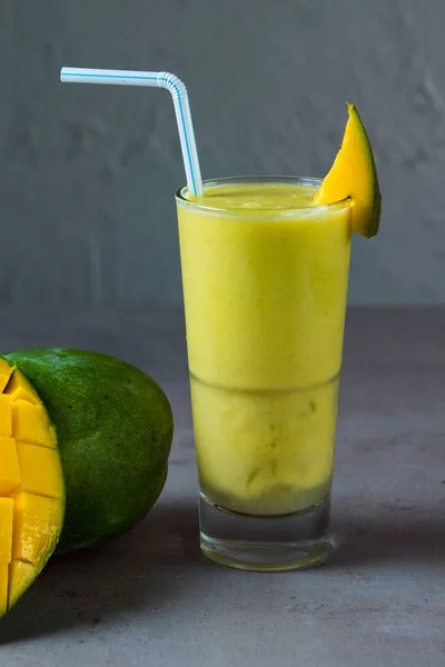 健康的なマンゴージュース新鮮なジュースは 灰色の背景にマンゴースライスと藁側のビューでガラスで提供しています — ストック写真