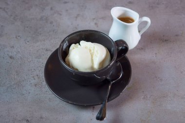 Kahve fincanında servis edilen sıcak Affogato, gri arka planda kaşık ve fasulye yan görünüşlü.