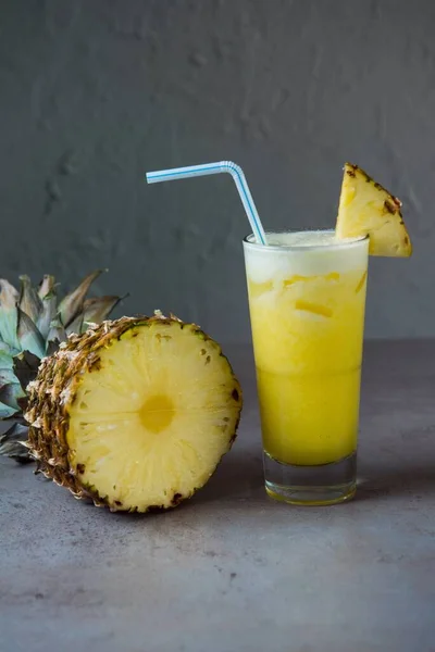 健康的なパイナップル新鮮なジュースは グレーの背景にパイナップルスライスとわら側のビューでガラスで提供しています — ストック写真