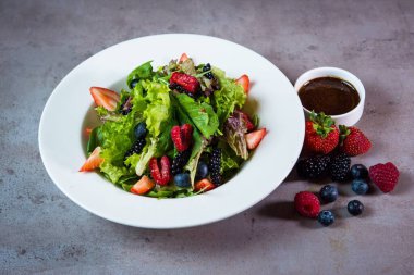 Bahreyn yiyeceklerinin arka planında, yaban mersinli, çilekli ve yabanmersinli karışık salata servis edilir.