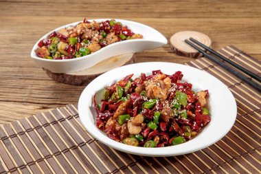 Baharatlı kırmızı biberli tavuk ve yemek çubukları, Hong Kong ahşap masasının üst manzarasında servis edilir.