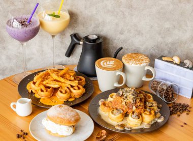 Mantar sütlü tavuk waffle, patates kızartması, kapuçino, moka latte sanat, karışık böğürtlen ve mango milkshake kahve çekirdekleri, çatal, kaşık tahtadan masa üstü Tayvan yemeği manzaralı.