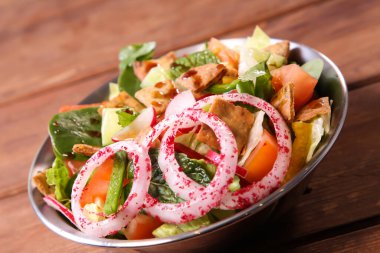 Fatoosh ya da Fatosh, domates, soğan ve salatalık arkaplanda soğuk mezzanın üstünde yalıtılmış olarak servis edilir.