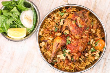 Baharatlı Bukhari Dajaj biryani, tüm tavuk, kaju fıstığı ve salata ile servis edilir.