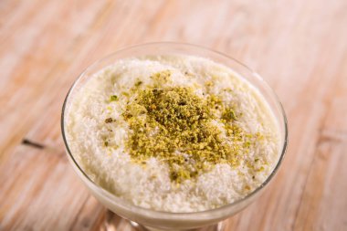 Masanın üstündeki Arap tatlısının üstünde yalıtılmış bir şekilde servis edilen muhallabia ya da Muhakabia tatlısı.