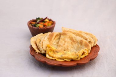 Kahvaltıda karışık sebzeler, yumurta omleti ve paratha arka planda yalıtılmış olarak servis edilir. Bangladesi kahvaltısının üst manzarası.