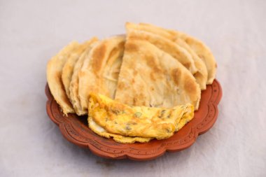 Kahvaltıda yumurta omleti ve paratha arka planda yalıtılmış, Bangladesi kahvaltısının üst görüntüsünde servis edilir.