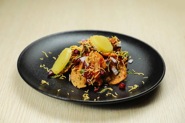 Aloo Papri Chaat, safra bhalla, patates, kraker, masala ve yoğurt arka planda izole edilmiş Hint baharatları sokak yemeklerinin üst görüntüsünde servis ediliyor.