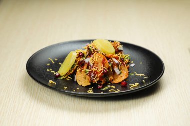 Aloo Papri Chaat, safra bhalla, patates, kraker, masala ve yoğurt arka planda izole edilmiş Hint baharatları sokak yemeklerinin üst görüntüsünde servis ediliyor.