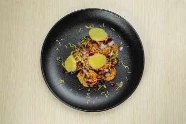 Aloo Papri Chaat, safra bhalla, patates, kraker, masala ve yoğurt arka planda izole edilmiş Hint baharatları sokak yemeklerinin üst görüntüsünde servis ediliyor.