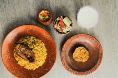Hilsa Khichuri Combo salata, patlıcan, borhani ve boondi rabi Hint ve Bangladeş yemeklerinin üst görüntüsünde servis edilir.