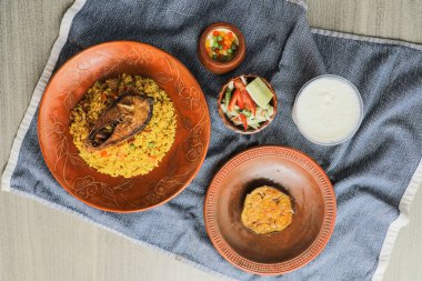 Hilsa Khichuri Combo salata, patlıcan, borhani ve boondi rabi Hint ve Bangladeş yemeklerinin üst görüntüsünde servis edilir.
