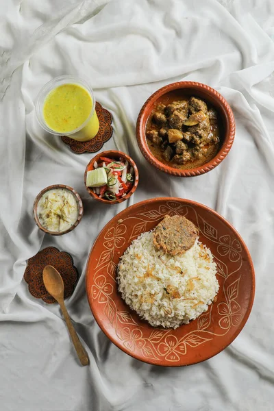 インド料理とバングラディッシュ料理のマットトップビューで隔離された料理で提供されるサラダ ボラーニーとチュイピサとシャトラ牛カッチビリヤニKichuri — ストック写真
