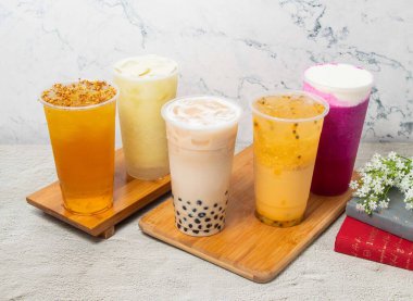 Çeşitli meyveli buzlu çaylar arasında Passion fruit, Pearl milk, Dragon Cheese Milk, Guava Lemonade ice, Osmanthus Oolong, Tayvan içkisinin arka planında izole edilmiş tek kullanımlık bardakta servis edilir.