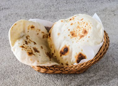 Pita ekmeği ya da Tandoori roti arka planda izole edilmiş sepetlerde servis edilir. Orta Doğu ve Hint yemekleri üst tarafta.