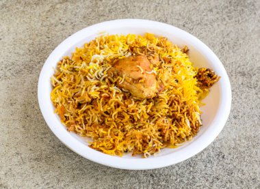 Baharatlı tavuk biryani pilavı. Gri arka planda, Pakistan ve Hint baharatlarının üst görüntüsünde servis ediliyor.