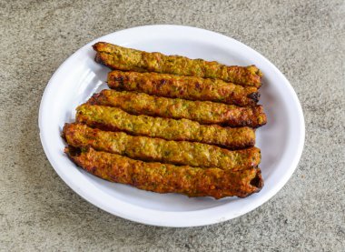 Baharatlı tavuk reshmi et kebabı. Gri arka planda Pakistan ve Hint baharatlarının üst görüntüsünde servis edilir.
