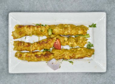 Baharatlı tavuk kebabı, arka planda Hint baharatları ve Pakistan yemekleri ile servis edilir.