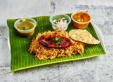 balık biryani pilavı salata, chutney, raita ve sos ile servis edilmiş muz yaprağı üzerinde Hindistan ve Singapur baharatlı yemekleri üst görünümü