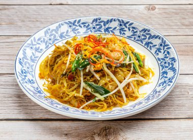 Singapur usulü kızartılmış pirinç vermicelli ahşap masa üstünde Hong Kong yemeklerinde servis edilir.