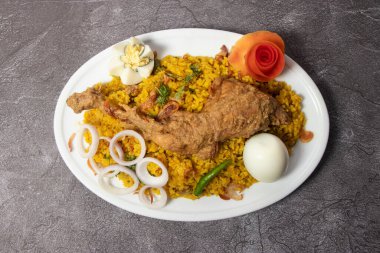 Tavuk Bhuna Khichuri biryani beyaz pirinç pulao haşlanmış yumurta ve kızarmış soğan arka planda izole edilmiş olarak servis edilir.