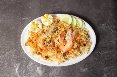 Salatalıklı karides Biryani pulao pilavı arka planda izole edilmiş olarak servis edilir. Bangladeş yemeğinin üst görüntüsü.