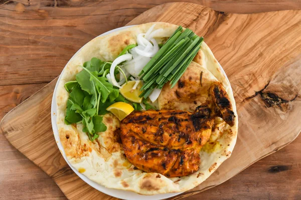 Tandoori chicken Chest with bahraini bread tandoori nan, lime and salad served in dish isolated on wooden table top view middle eastern grills food