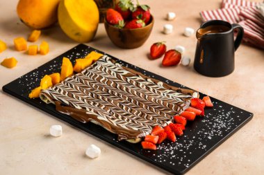 Nutella chocolate crepe garnished with strawberry and mango slice served in dish isolated on table top view of cafe dessert clipart