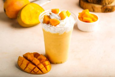 Kremalı ve çiğ meyve dilimli mango milkshake. Masanın üstünde izole edilmiş. Sağlıklı sabah içeceği.