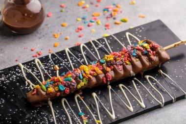 Çikolatalı ve karamel kaplı Gökkuşağı Waffle In Stick. Masanın üstünde gözleme ve tatlı olarak servis edilir.