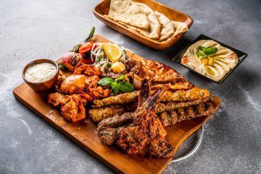 Izgarayı şiş tawook, koyun pirzolası, şampiyon, tavuk kebabı, sığır kebabı, tikka boti, reshmi ve malai, humus, pita ekmeği, tandır roti, raita, salata ve limon ile karıştırın.