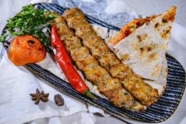 Pide, domates ve soğanlı tavuk kebabı. Yemek masasında servis ediliyor. Orta doğu baharatlarının üst görüntüsü.