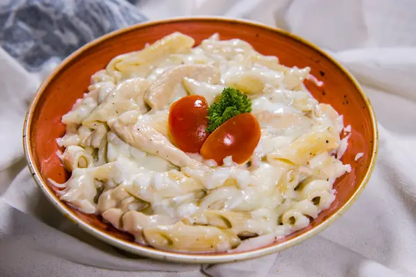 Chicken Pasta in white sauce with tomato served in dish isolated on food table top view of middle east spices