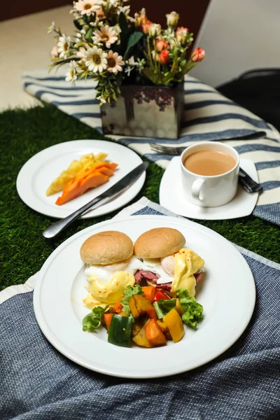 本尼迪克特蛋卷加蔬菜沙拉包括西红柿 莴苣叶和胡萝卜加茶 咖啡和甜瓜 放在饭桌上可以看到健康的英式早餐 — 图库照片