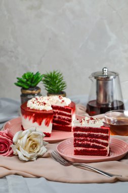 Kaliteli kırmızı kadife kek ve dilimler arasında krema, çatallı şeker, bir fincan kahve ve kahve yer alıyor.