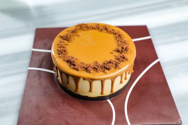 Tuzlu Karamelli Sarışın kek, çikolatalı krema, çatallı şeker, bir fincan kahve ve kafeterya manzaralı peçete tarafında servis edilen çömlek