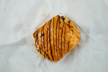 Çikolatalı kruvasan gri arka planda izole edilmiş. Fransız kahvaltısının üst görüntüsü. Gri arka planda pişmiş gıda öğesi.