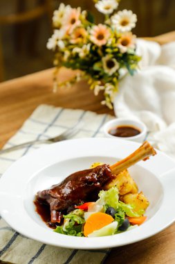 Kuzu Ossobuco ya da Osso buco kuzu budu patates, sos ve salata tabakta servis edilir peçetenin yanında et yemeği manzarası izole edilir